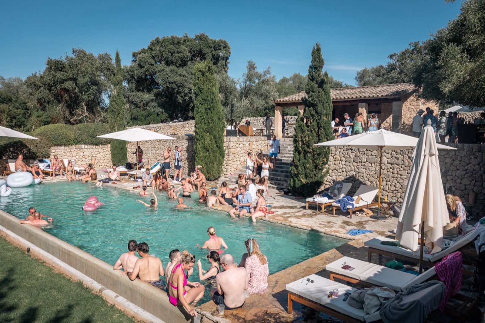 Guests swimming and sitting around a villa pool in Mallorca